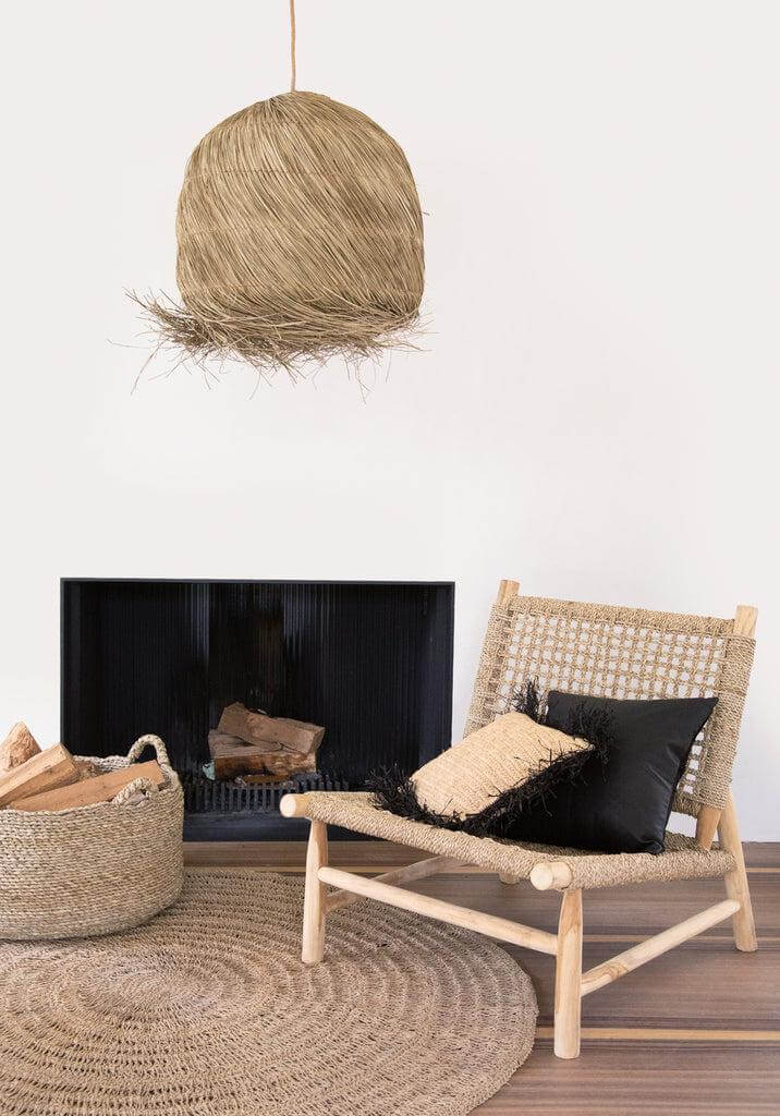 Stijlvolle woonkamer met raffia kussenhoes 40x40 in naturel zwart op houten stoel bij haard. Perfect voor boho interieur.