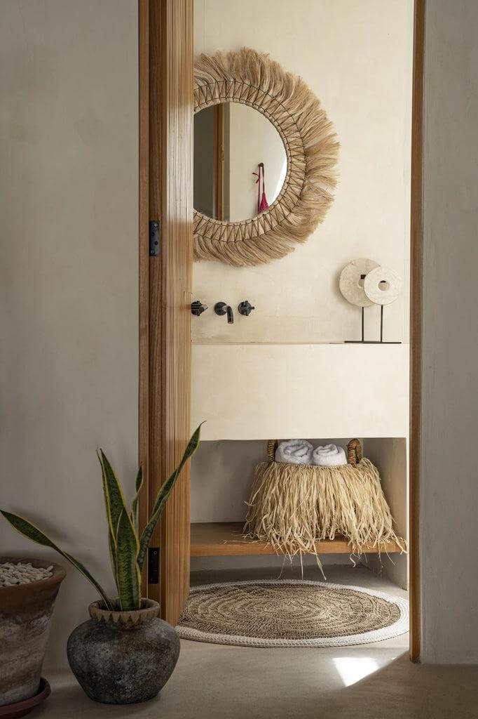 Alt Tag: Tropische badkamer met raffia mand en spiegel, rustiek interieur met planten en rotan decor.