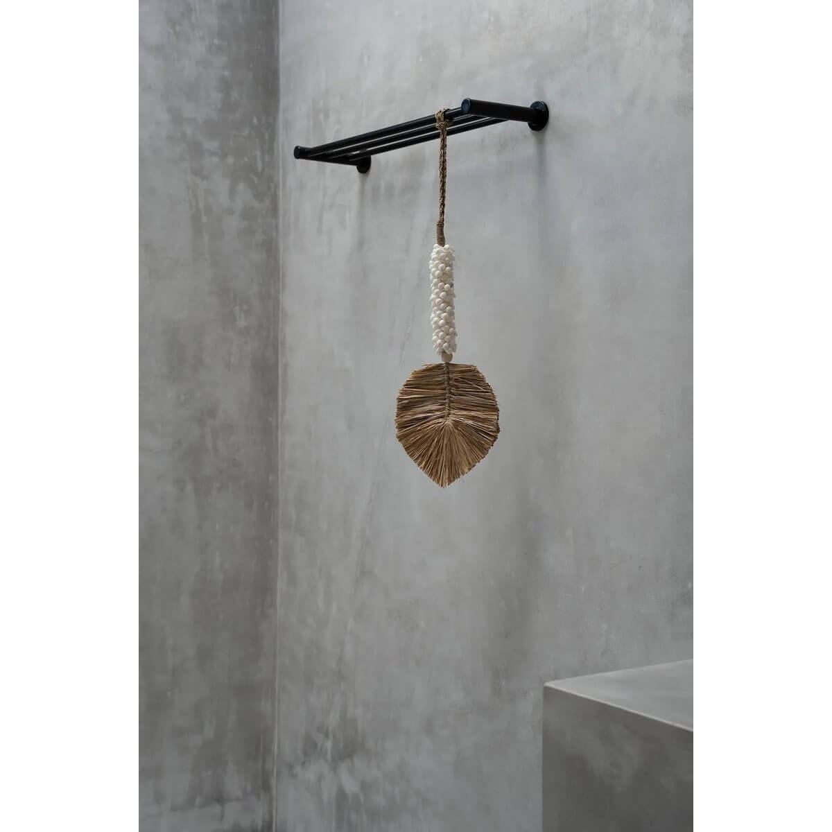 Bohemian raffia shell tassel in white and beige, handmade by Balinese artisans, hanging on a minimalist wall hook for chic home decor.