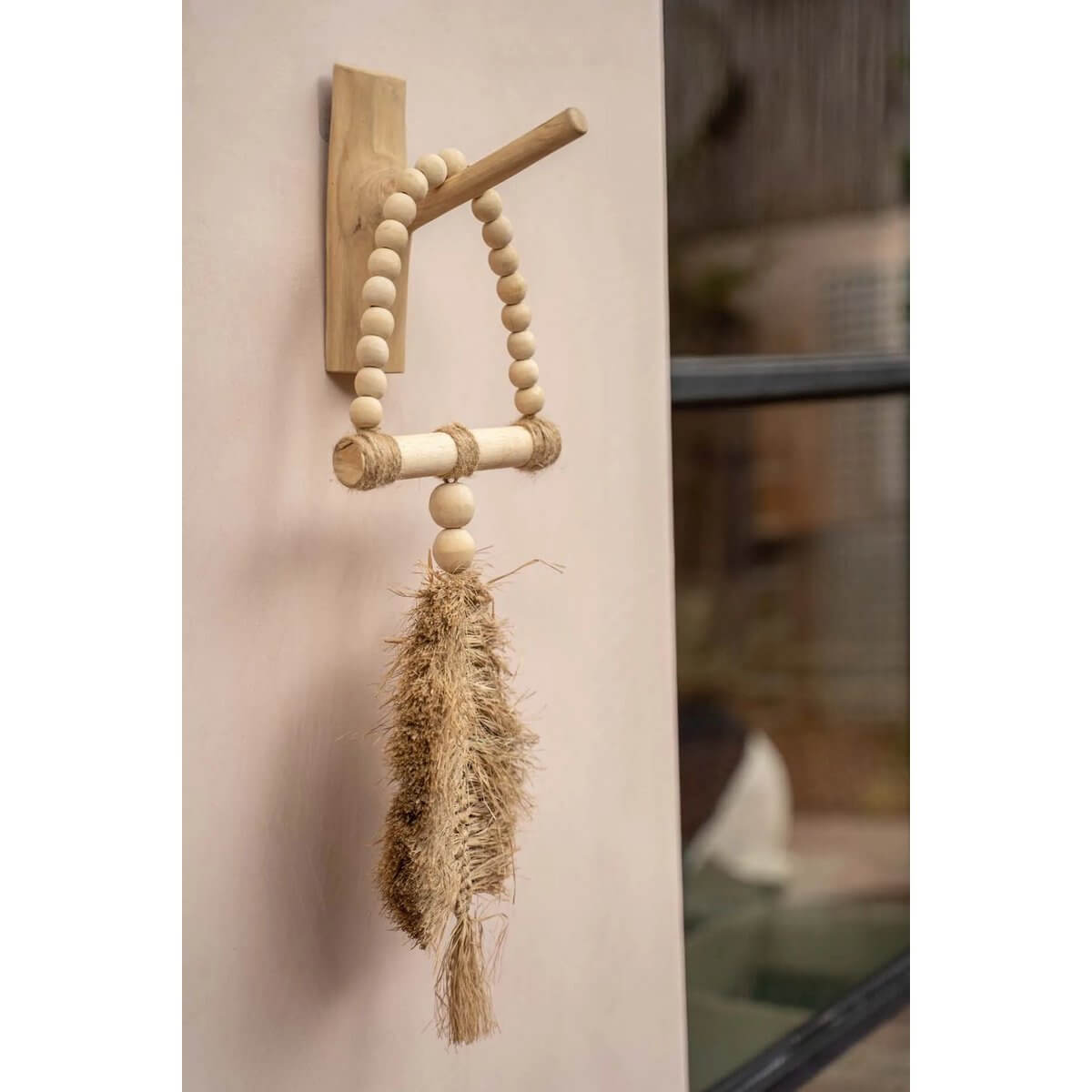 De Raffia-driehoek bohemian tassel decor hanging on a wall, handmade from raffia by Balinese artisans, adds exotic charm to home decor.