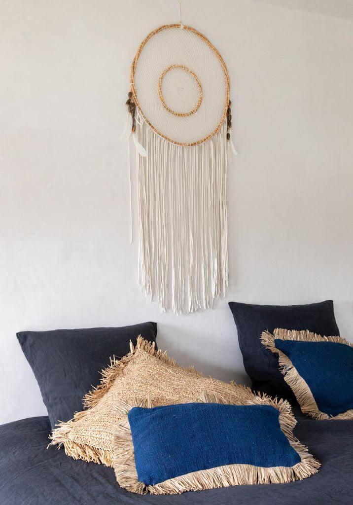 Blauw en natuurlijk kussenhoes van De Saint Tropez op bed, met katoen en raffia franjes. Perfect voor boho interieur. Afmeting: 30x50 cm.