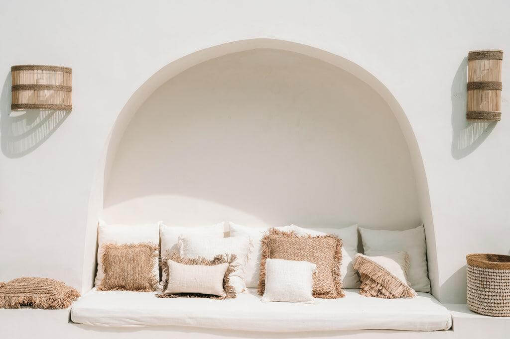 Stijlvolle boho zithoek met natuurlijke kussens en raffia accenten voor een ontspannende villa-uitstraling in naturel wit.