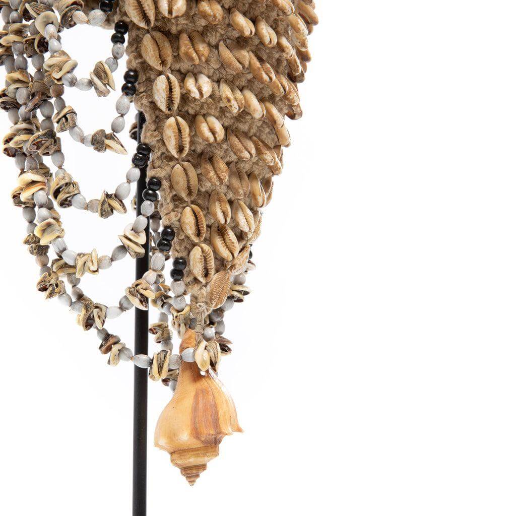 Handgemaakte hoed met schelpen en veren op standaard, geïnspireerd door Balinese stranden, in natuurlijke en zwarte kleuren.