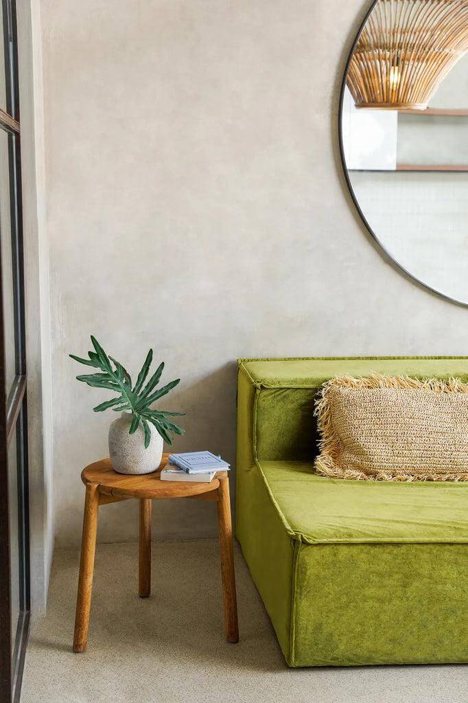 Stijlvolle groene zithoek met Seseh bijzettafel van teakhout en plant, naast ronde spiegel. Perfect voor binnen en buiten.