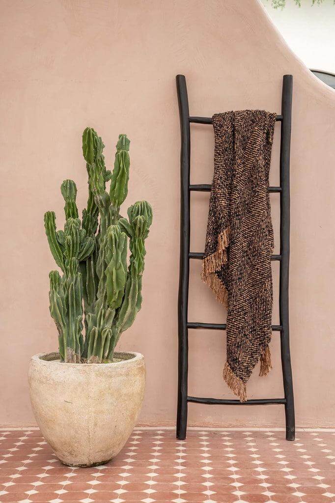 Stijlvolle zwarte koperkleurige katoenen plaid op een houten ladder naast een cactus, perfecte aanvulling voor een gezellige sfeer.