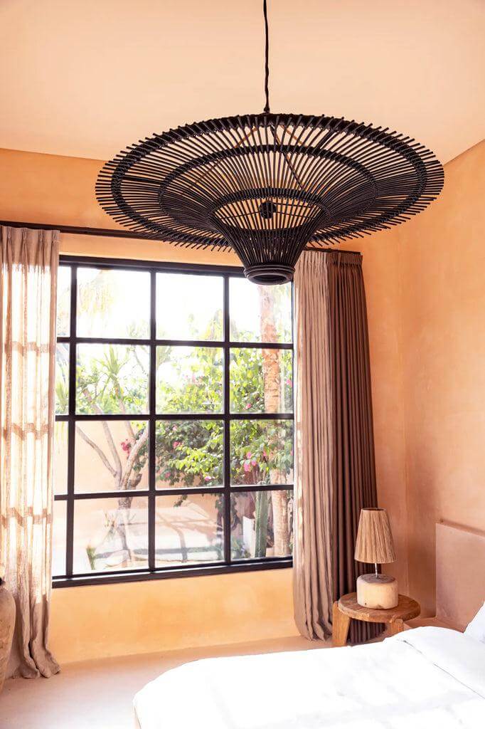 Stijlvolle zwarte XXL De Sky hanglamp van rotan in een modern interieur met grote ramen en warme kleuren.