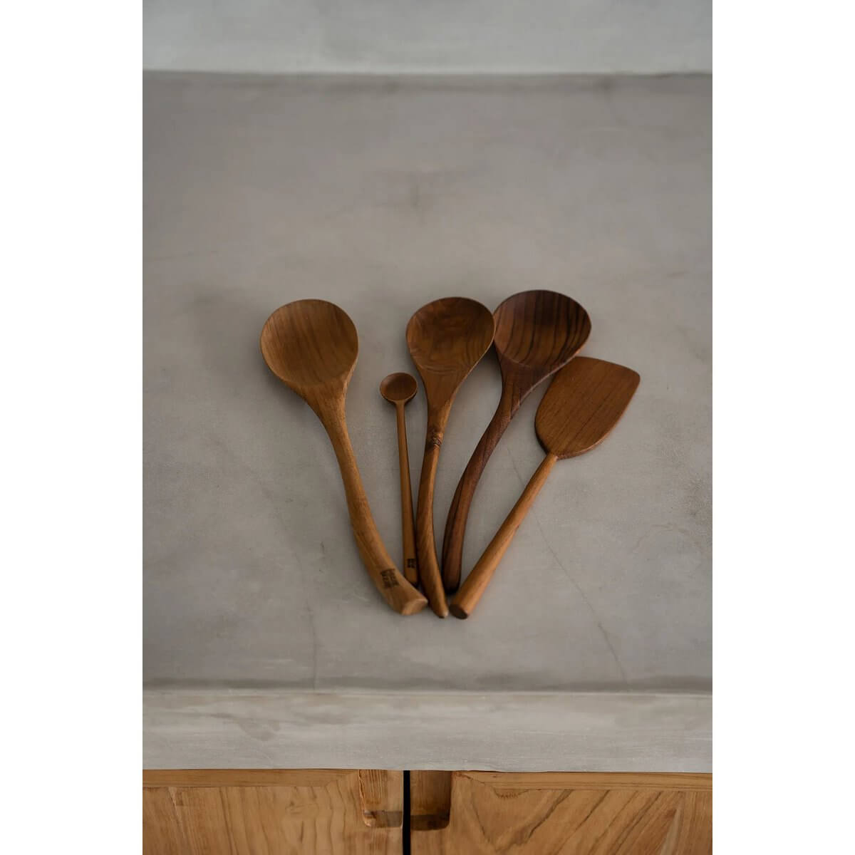 Collection of teak wood spatulas on a kitchen countertop, showcasing sustainable Bohemian kitchenware by Bazar Bizar Living.