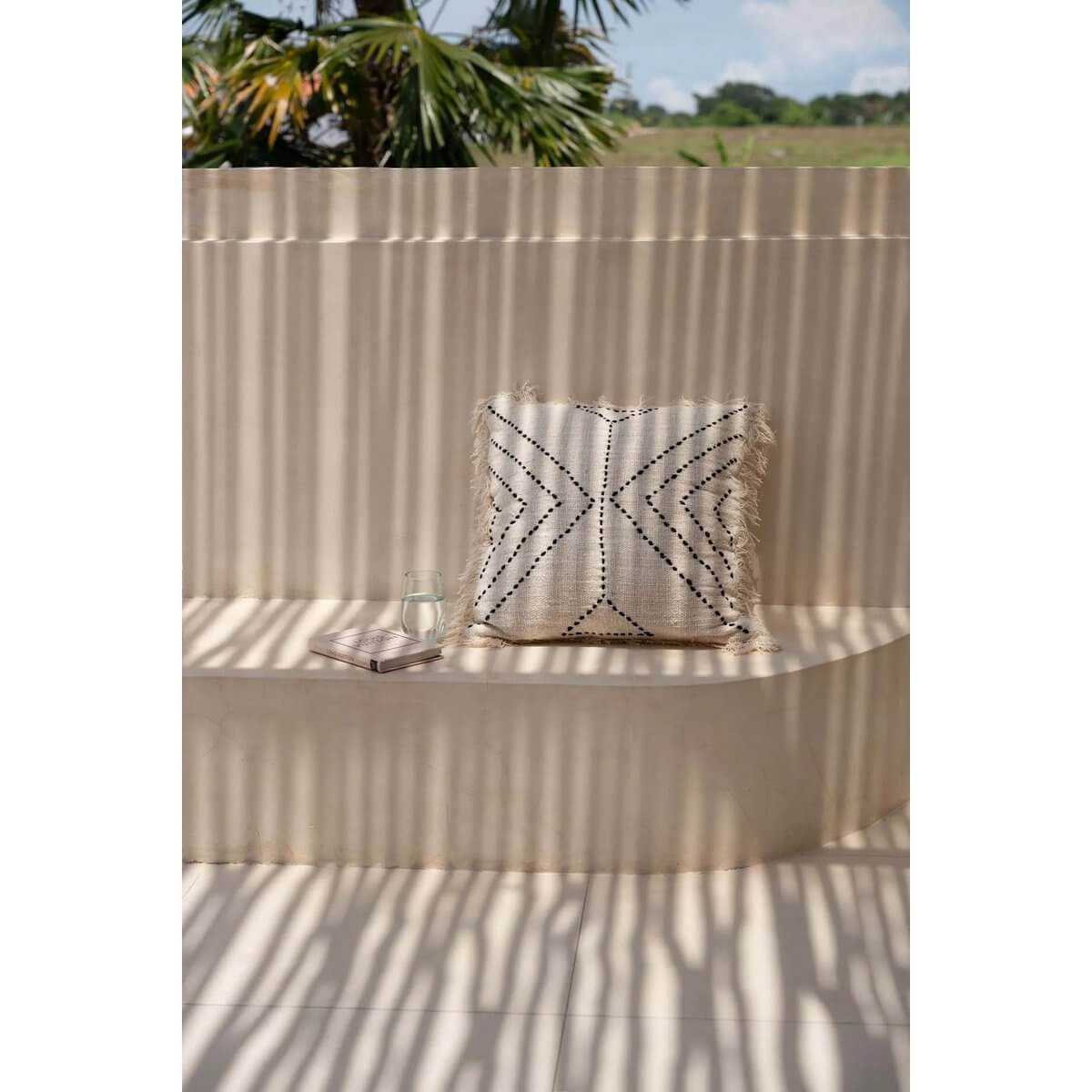 Kussenhoes met tribal patroon in zwart op een buitenbank, voegt een culturele sfeer toe aan uw interieur.