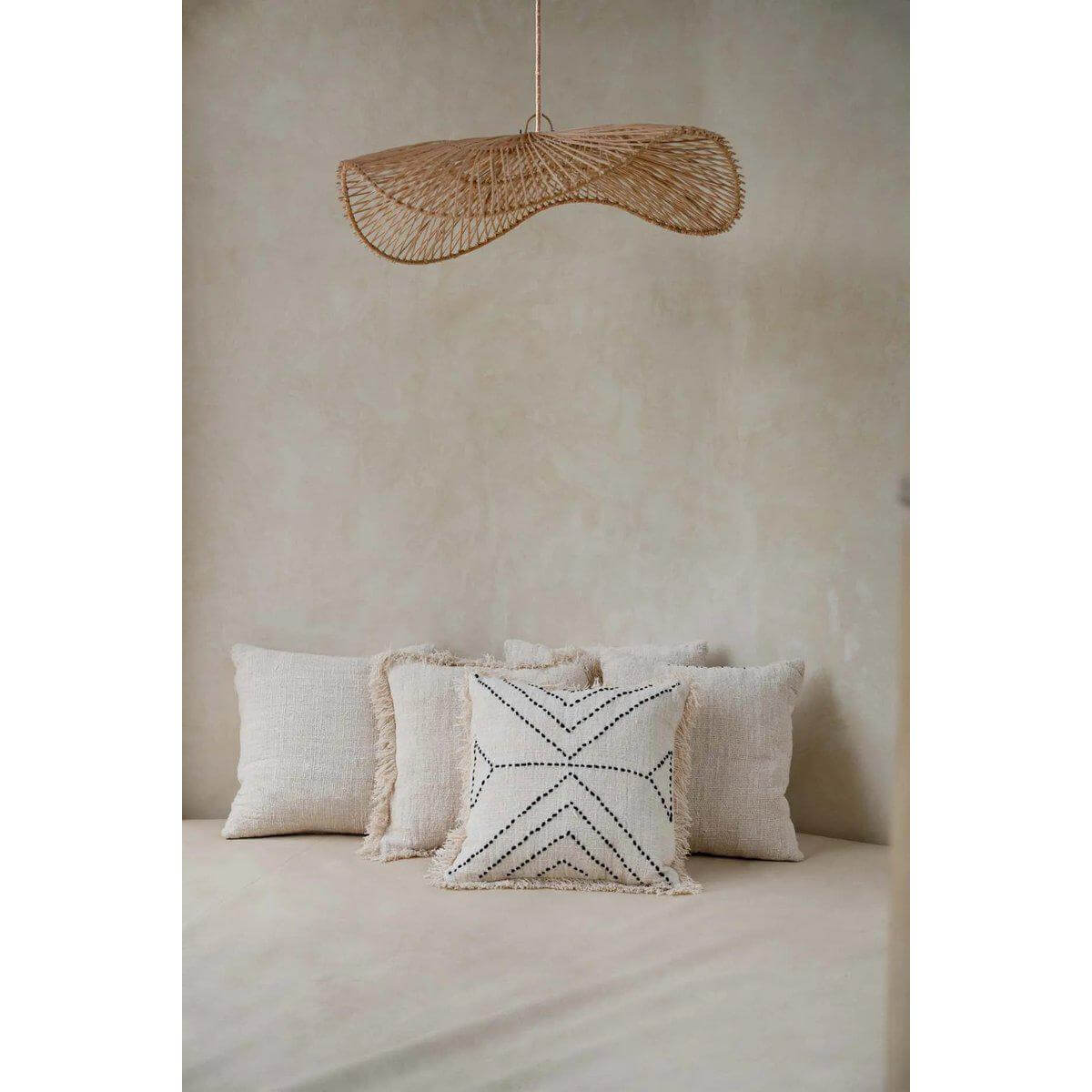 Stijlvolle kamer met natuurlijke zwarte tribal kussenhoes en moderne rieten hanglamp.