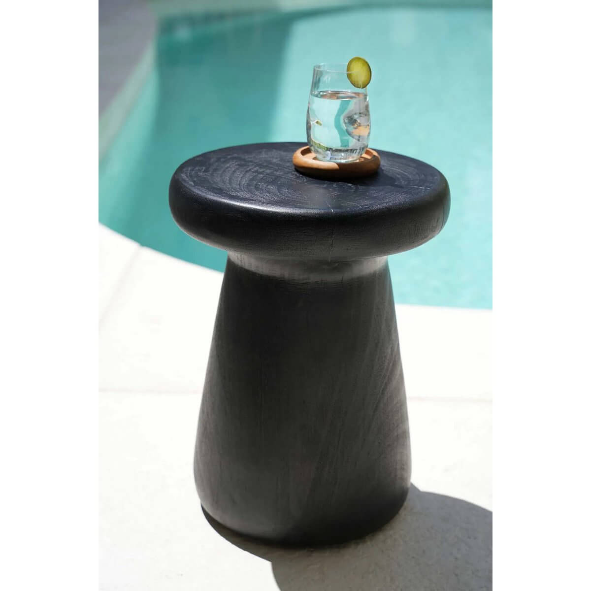Bohemian VIP coaster holding a glass by the pool on a stylish black side table, perfect for adding natural sophistication to your decor.
