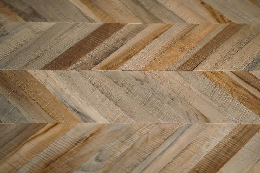 Close-up van een elegant visgraatpatroon in naturel teakhout, perfect voor een stijlvolle en inklapbare eettafel of bank.
