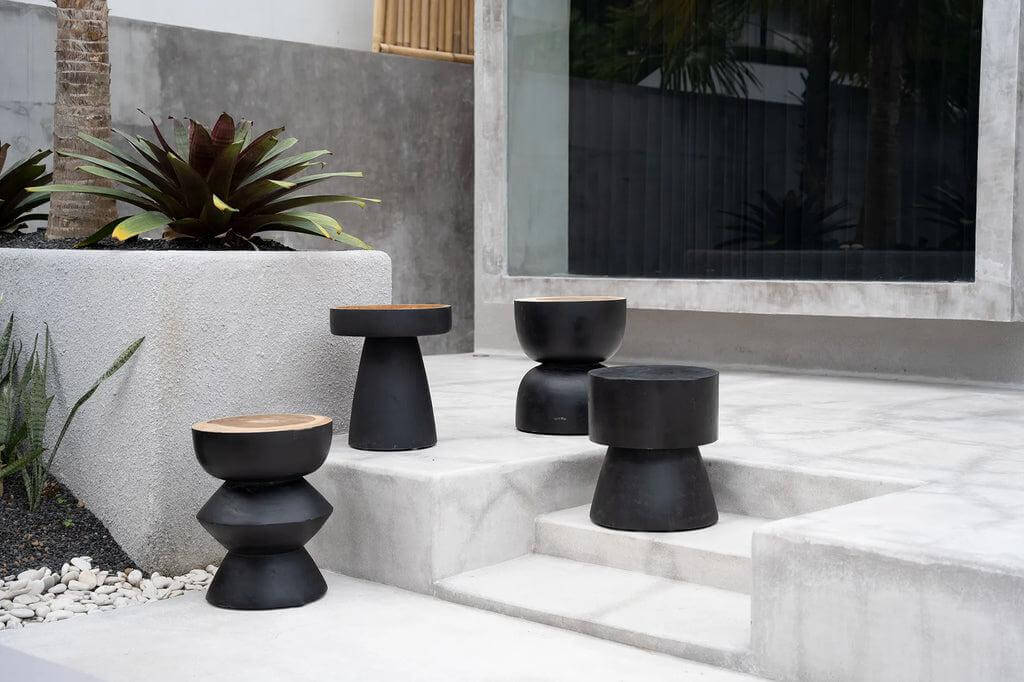 Moderne zwarte bijzettafels in futuristisch design op een terras met planten, Warmi kruk, duurzaam suarhout, interieur statement.