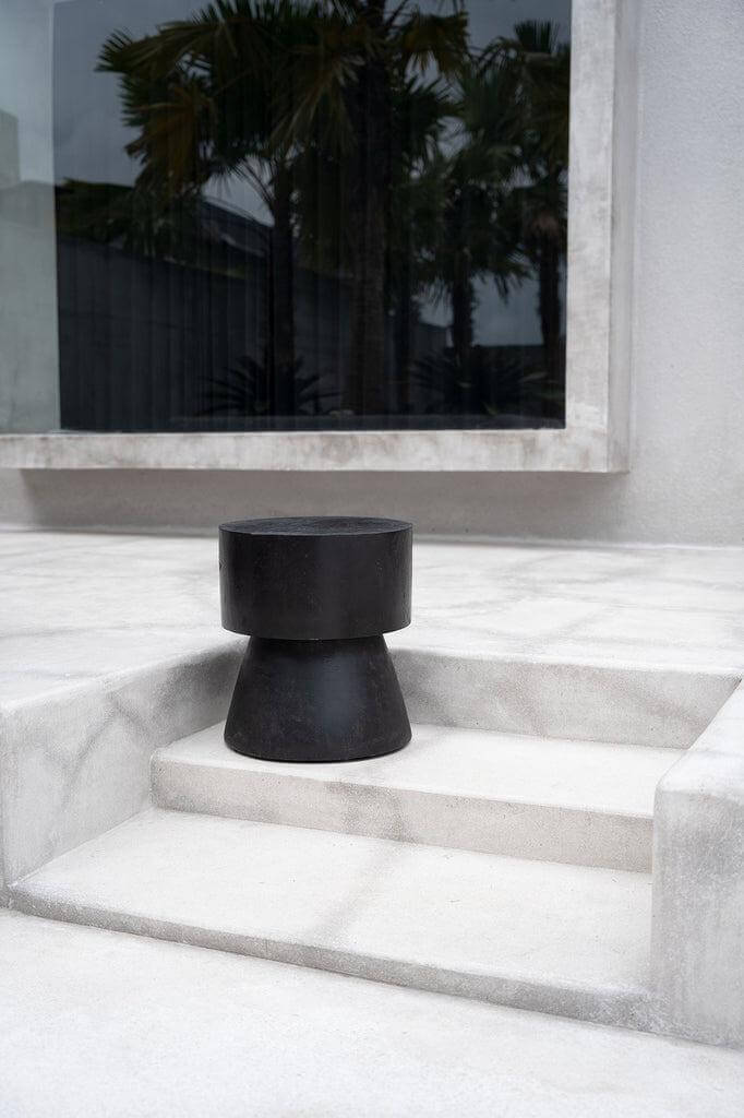 De Warmi Kruk in zwart suarhout, modern design op marmeren terras.