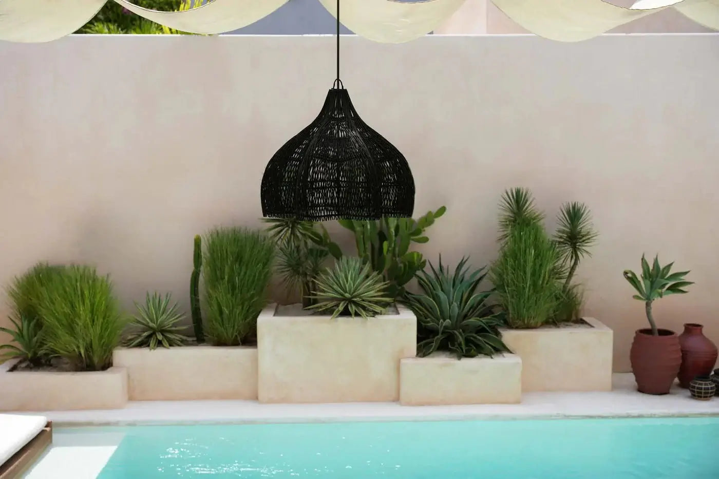 Boho stijl De Whipped Hanglamp zwart - M in een moderne tuin bij een zwembad met exotische planten.