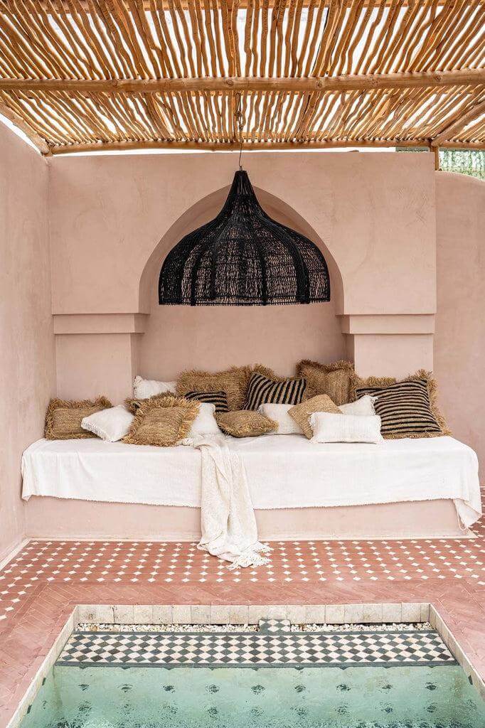 Alt Tag: Grote boho chic hanglamp in zwarte rotan boven een stijlvolle loungehoek in een zomerterras, geen bekabeling inbegrepen.