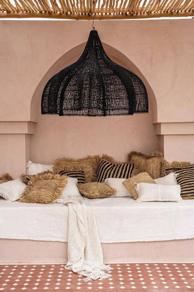 Grote zwarte rotan hanglamp boven boho chic zithoek met kussens, ideale XL lamp voor interieur of overdekt buiten.