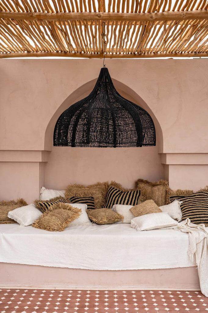 Zwarte XL rotan hanglamp in boho chic stijl boven lounge zithoek.