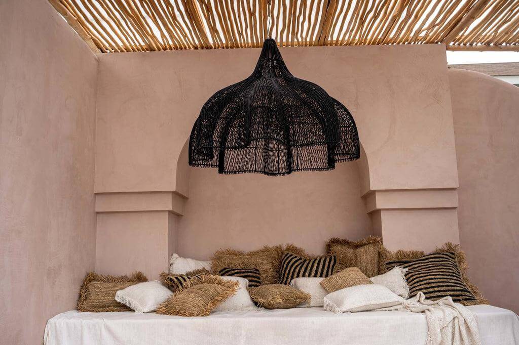 Alt Tag: De Whipped Hanglamp Zwart XL in een boho chic kamer met kussens, rotan design, 110 cm hoog, geen bekabeling inbegrepen.