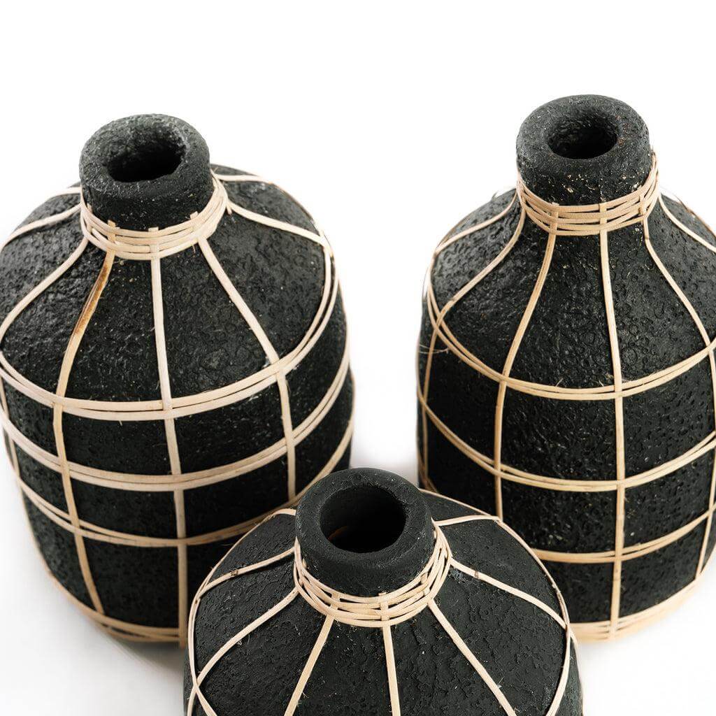 De Whoopy Vaas in zwart met rotan details, perfect voor droogbloemen, geeft een kustgevoel aan je interieur. Hoogte 19 cm.