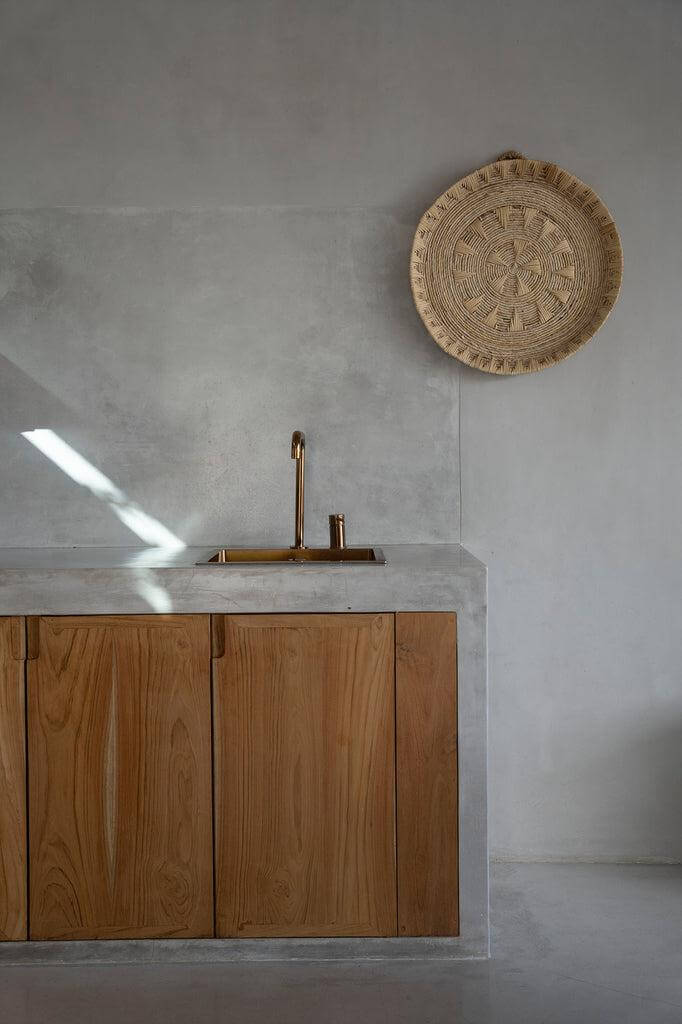 Stijlvolle woonkamer met De Xolo muurdecoratie van bananenblad op een neutrale muur boven houten kastjes.