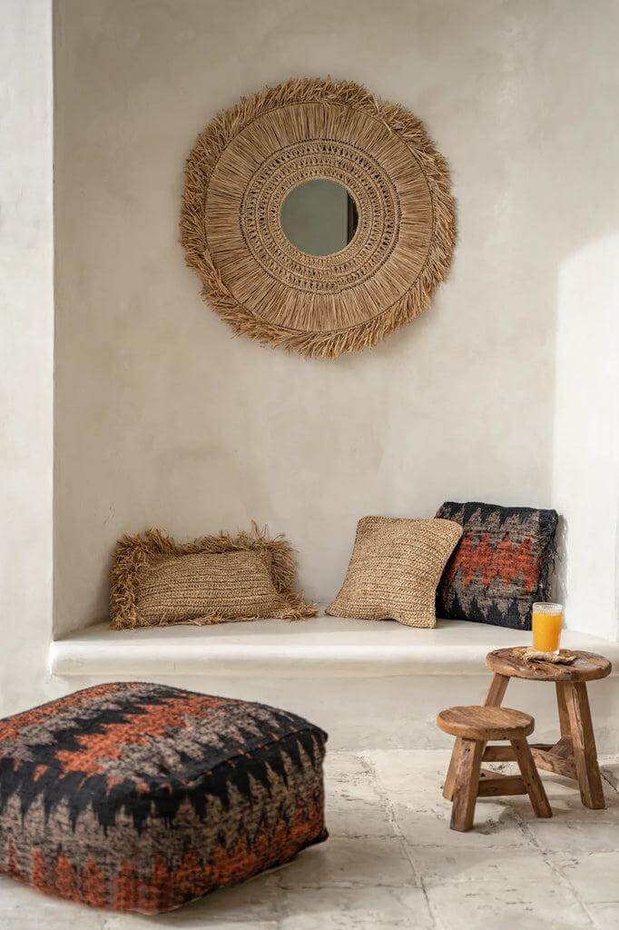 Gezellige zithoek met Yatai kruk van teakhout, sierkussens en decoratieve spiegel in boho-stijl. Perfect voor sfeervol interieur.