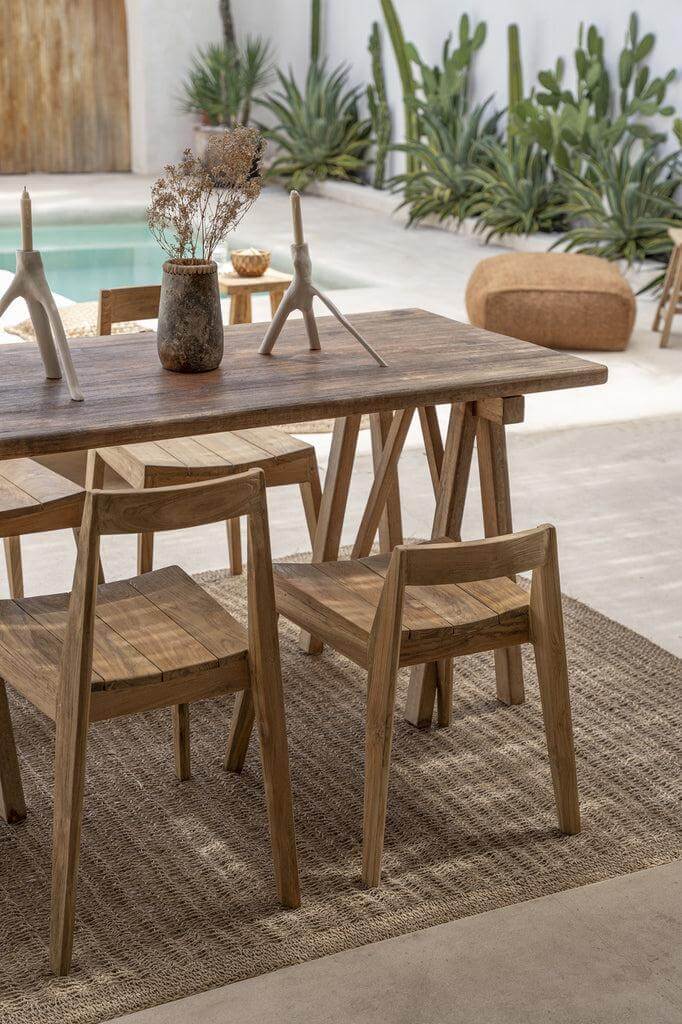 Alt Tag: Stijlvolle Ydra eetkamerstoel van gerecycled teakhout in een elegante buitenomgeving met planten en zwembad.