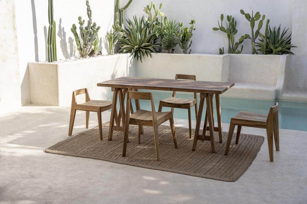 Stijlvolle Ydra eetkamerstoel in een moderne buitenruimte met cactussen, gemaakt van gerecycled teakhout. Elegantie en duurzaamheid.
