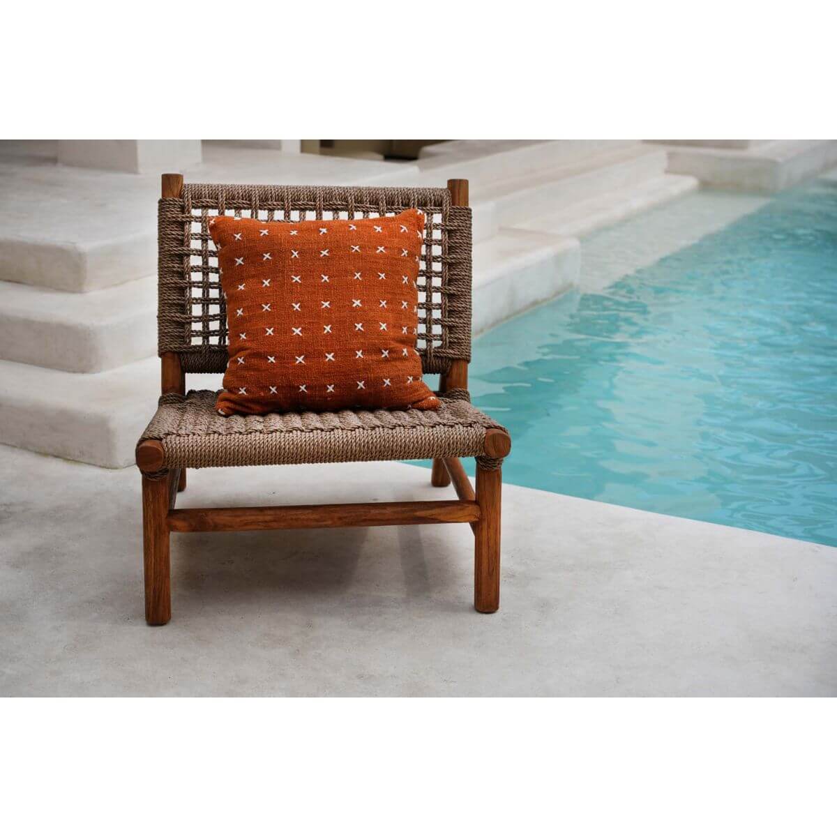 Terracotta wit Zillion Kiss kussenhoes op een stoel bij een zwembad, warme en aardse tinten voor luxe woondecor.