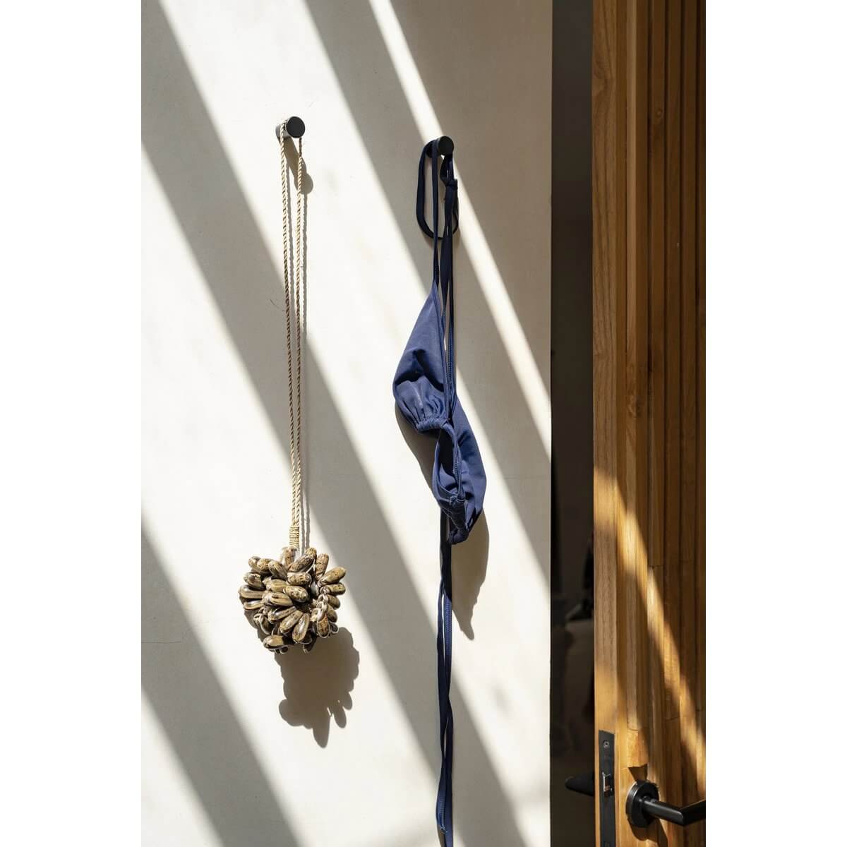 Handmade brown Kauri shell tassel on a wall, adding exotic Bohemian charm to home decor from Bazar Bizar Living.