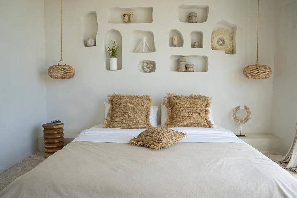 Bohemian slaapkamer met rustiek bed en rieten decoratie op witte muur, sfeervolle inrichting voor ontspannen sfeer.
