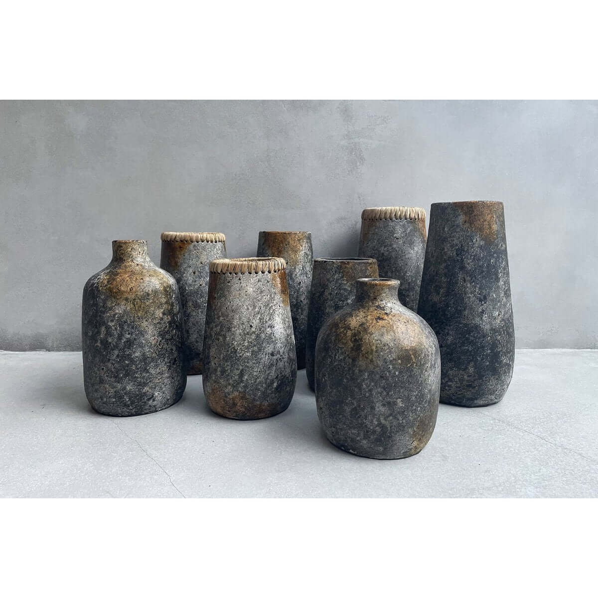 Collection of antique grey terracotta and rattan vases by Bazar Bizar Living, showcasing Bohemian rustic charm in various shapes.