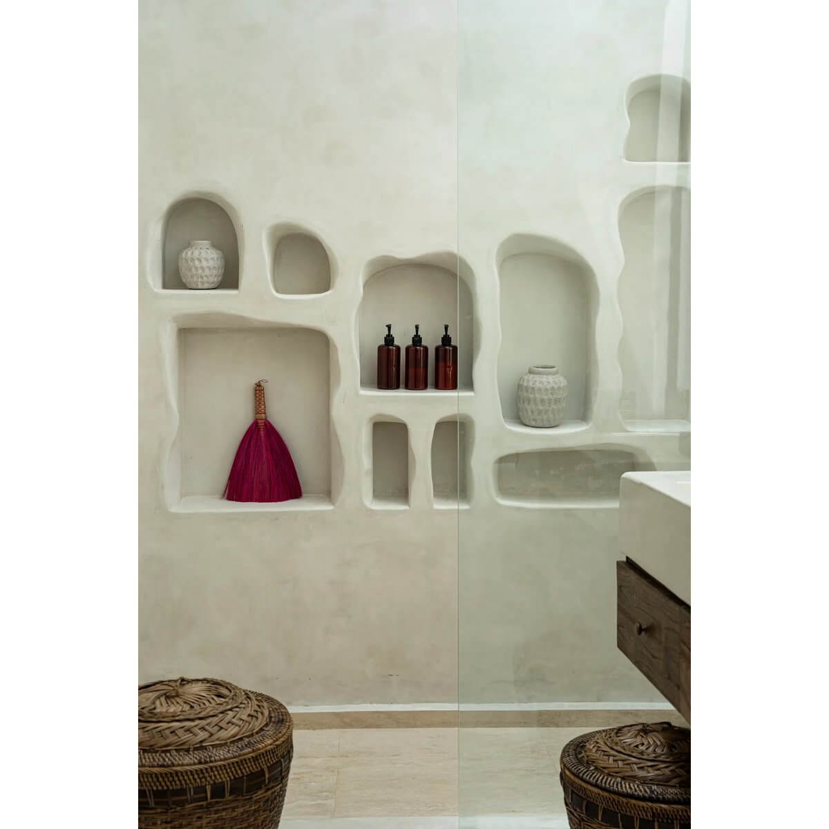 Bohemian style pink Indonesian hand broom displayed on a shelf in a stylish neutral bathroom with rustic decor.