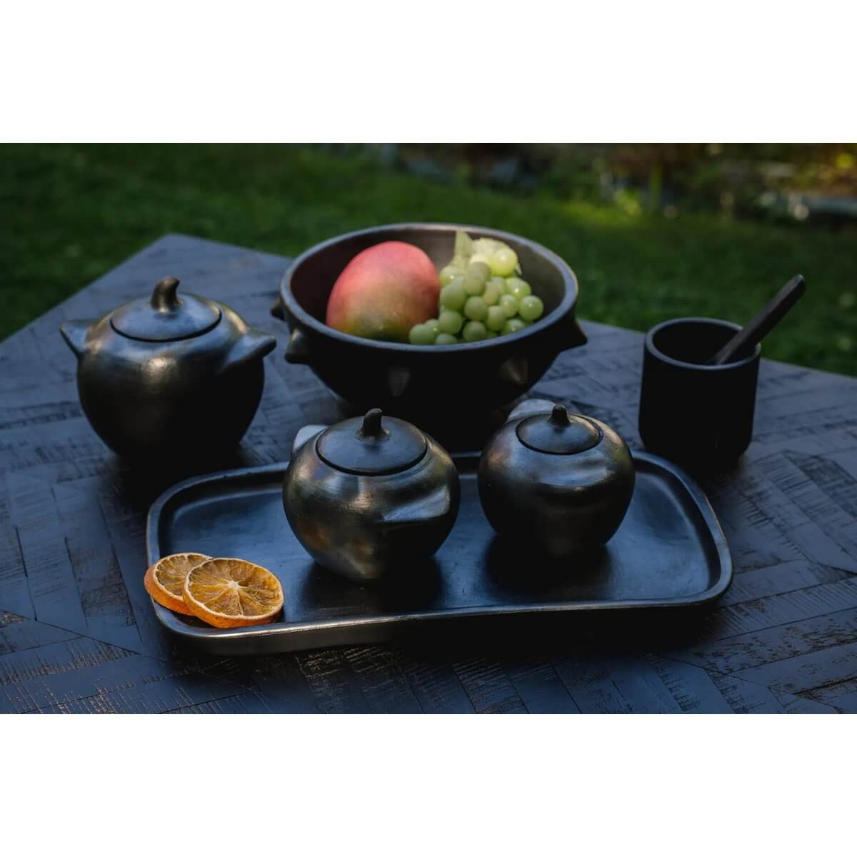 Bohemian Burned Collection pottery with fruits outdoors.