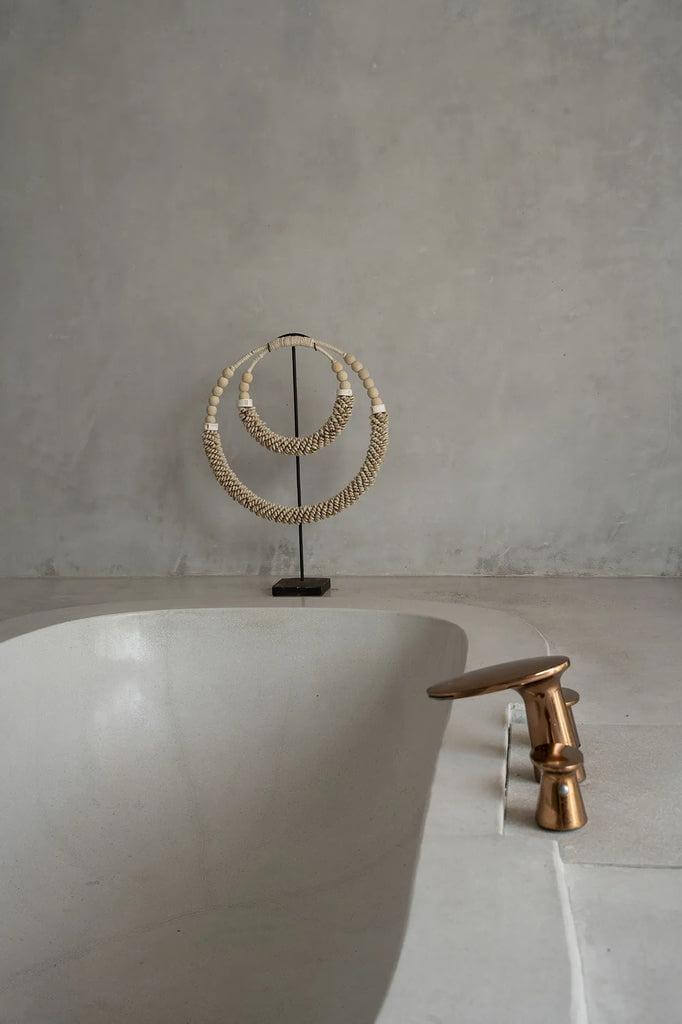 Dubbele halsketting met schelpen op standaard in moderne badkamer, natuurlijke kleuren, handgemaakt door Balinese ambachtslieden.