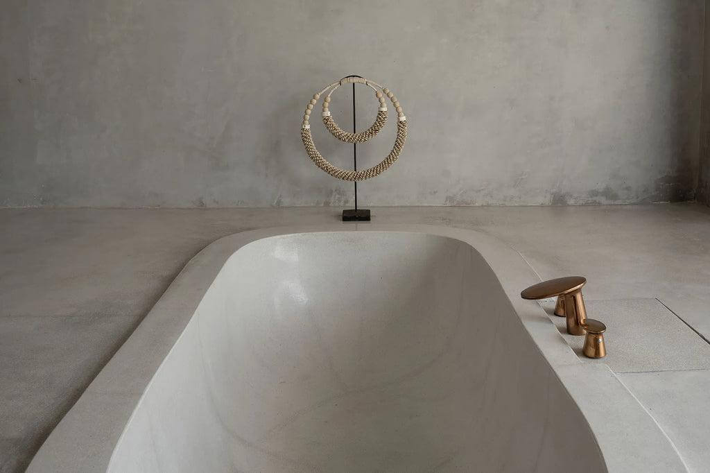 Stijlvolle dubbele halsketting met schelpen, bot en kralen op standaard als badkamerdecoratie. Balinese ambacht in natuurlijke kleuren.