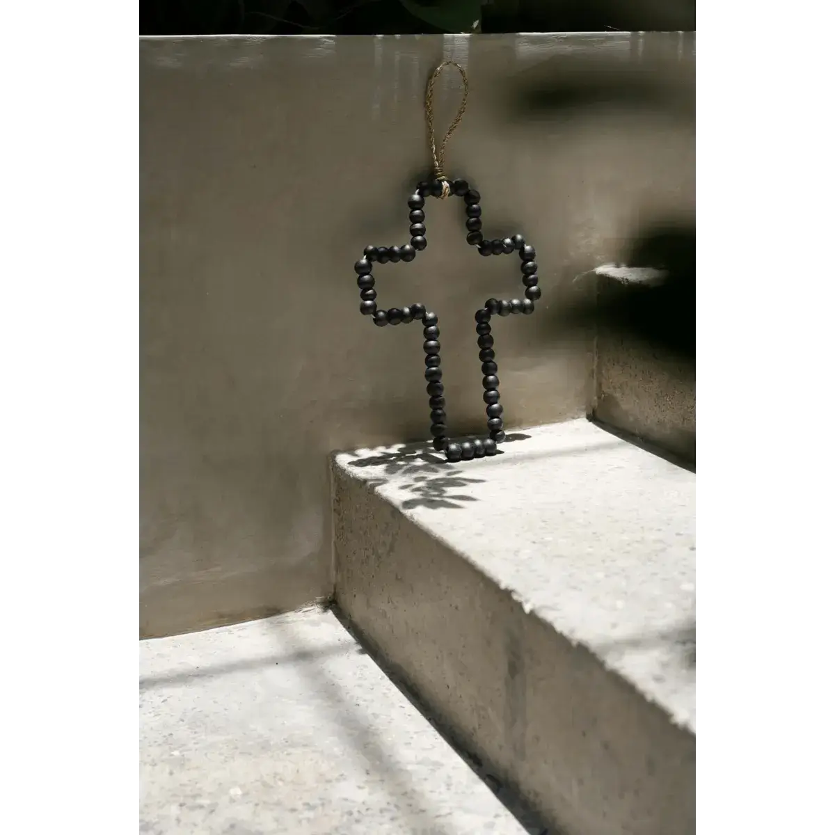 Bohemian style black wooden bead cross decor on steps, handmade by Bazar Bizar Living. Ideal for home decoration. Size: 22x1x40cm.