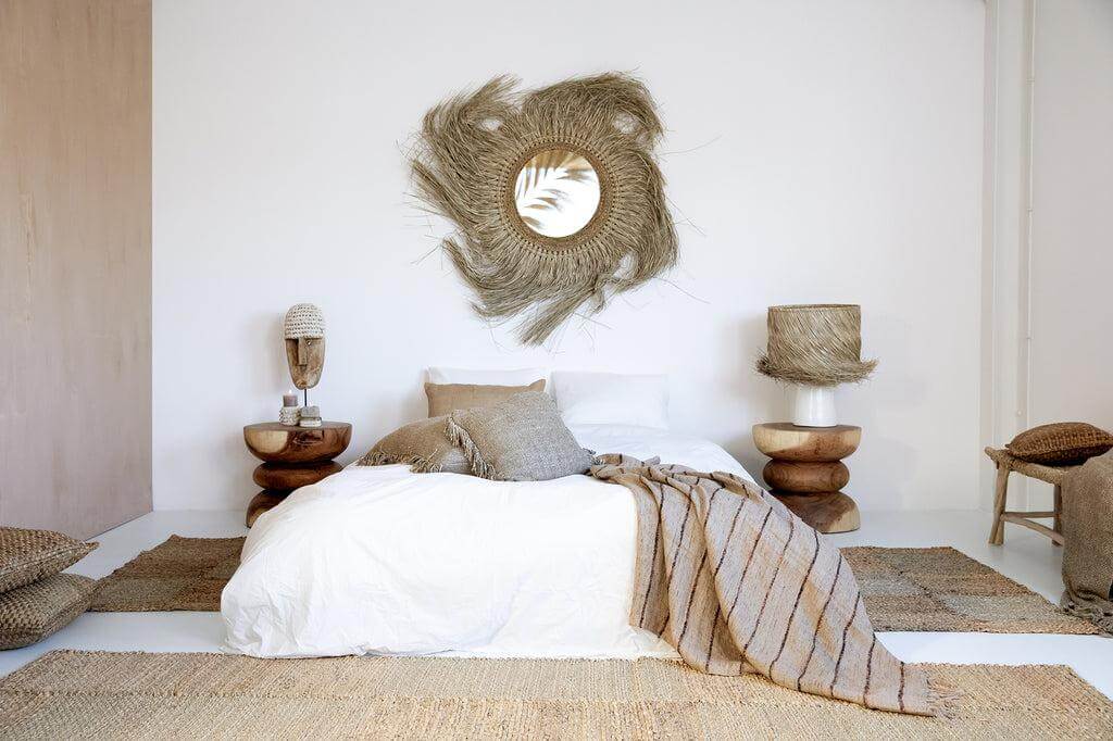 Gezellige boho slaapkamer met handgeweven waterhyacint elementen en natuurlijke kleuren, inclusief het Hyacint Kussen op een wit bed.