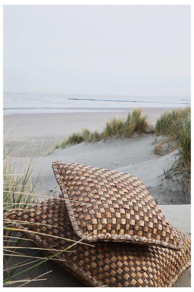 Handgeweven waterhyacint kussen op een strand, voegt boho stijl toe aan woon- of tuininrichting. Natuurlijke textuur en kleur.