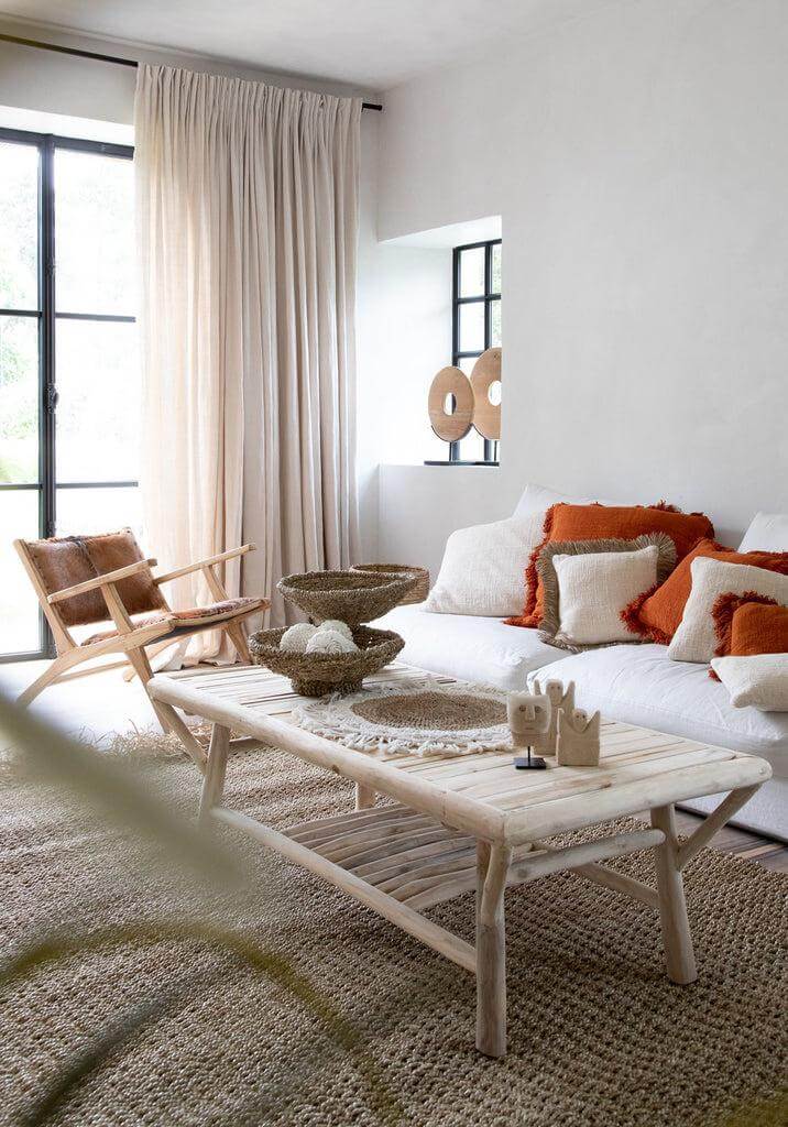 Gezellige woonruimte met naturel franjestapijt van raffia, sisal en palm, omringd door comfortabele witte meubels en houten accenten.