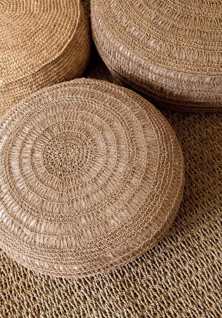 Alt Tag: Handgeweven natuurvezel kussens op een raffia tapijt, biedt een warme en natuurlijke look voor elke interieurstijl.