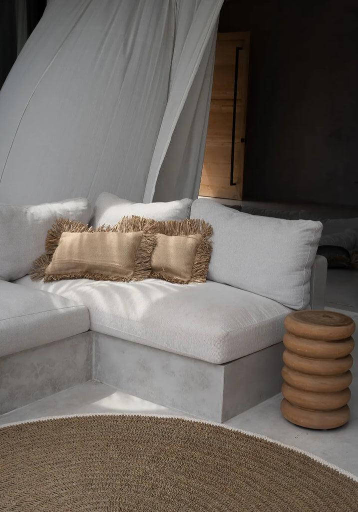Gezellige woonkamer met rond zeegras tapijt in naturel wit, naast een stijlvolle hoekbank en decoratieve kussens.