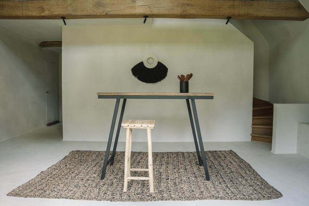Moderne kamer met zeegras tapijt in natuurlijke en zwarte kleuren, eenvoudige tafel en krukje. Perfect voor keuken of terras.