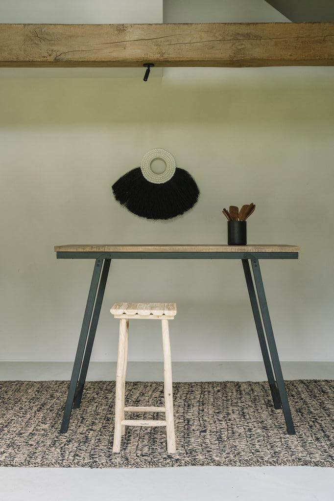 Gezellig Scandinavisch interieur met zeegras tapijt in naturel zwart, een houten kruk en een minimalistisch bureau.