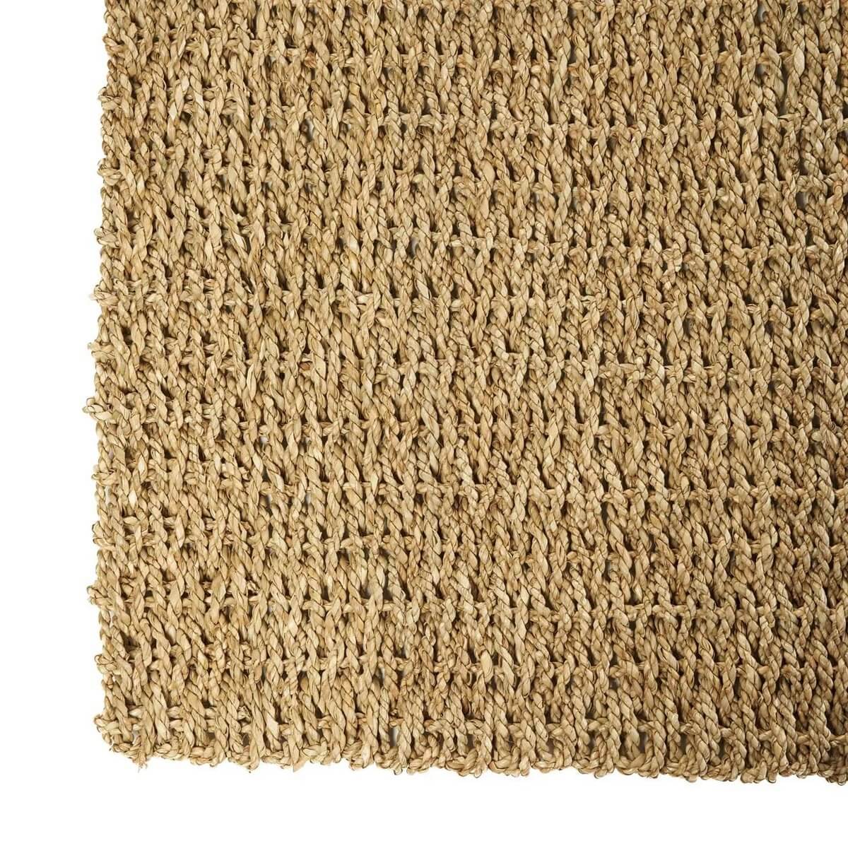 Close-up of Het Sizali Tapijt, a natural woven sisal carpet, showcasing its warm texture for a Bohemian home vibe.