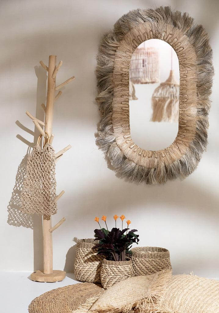 Stijlvolle boho woonkamer met natureltinten, inclusief waterhyacint tapijt en rustieke wandspiegel.
