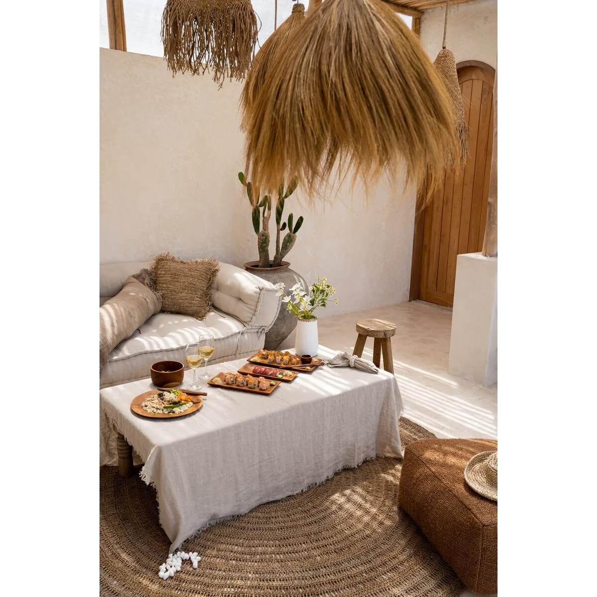 Luxe beige linnen tafelkleed op een rustieke tafelsetting met hapjes en planten voor een stijlvolle eettafeldecoratie.