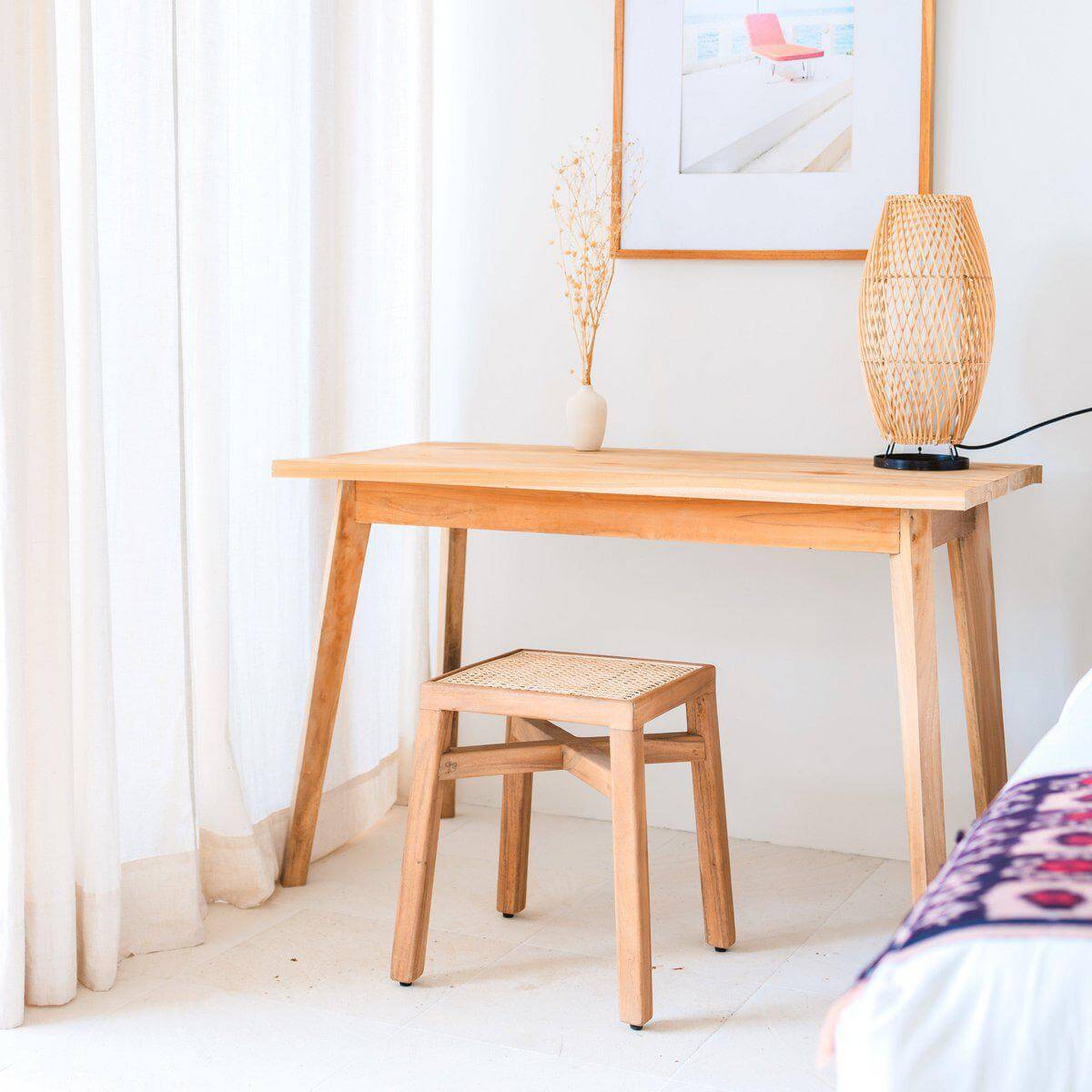 Stijlvolle houten kruk SUBANG van duurzaam regenboomhout met rotan, geplaatst bij een houten schrijftafel in een lichte kamer.