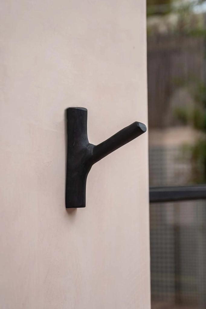 Kapstok The Hook Zwart van teak, gemonteerd op een muur, ideaal voor een kust-sfeer in de slaapkamer of badkamer. Stijlvolle eenvoud.