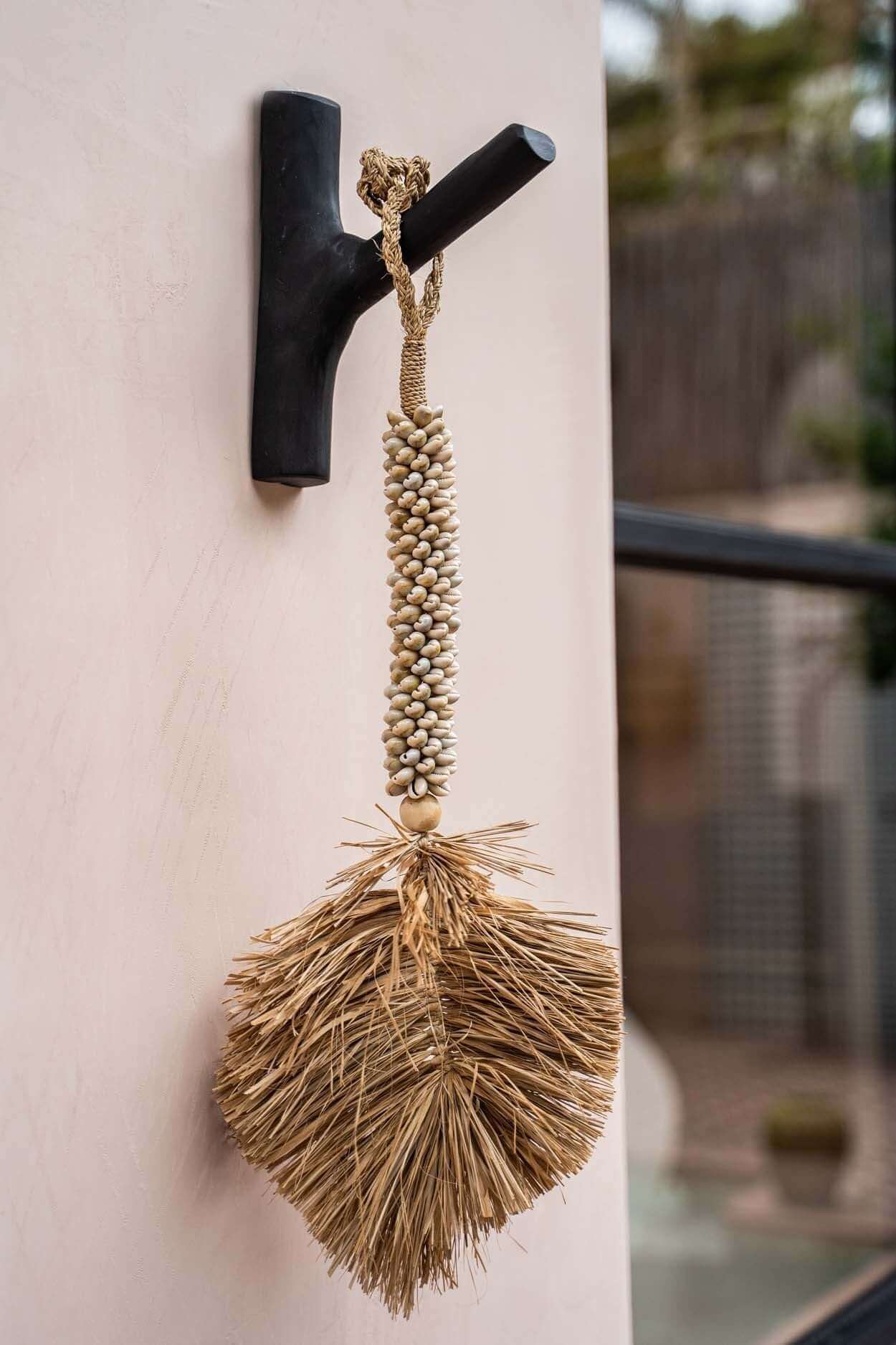 Kapstok The Hook Zwart met decoratieve hanger vol kust-sfeer aan de muur.
