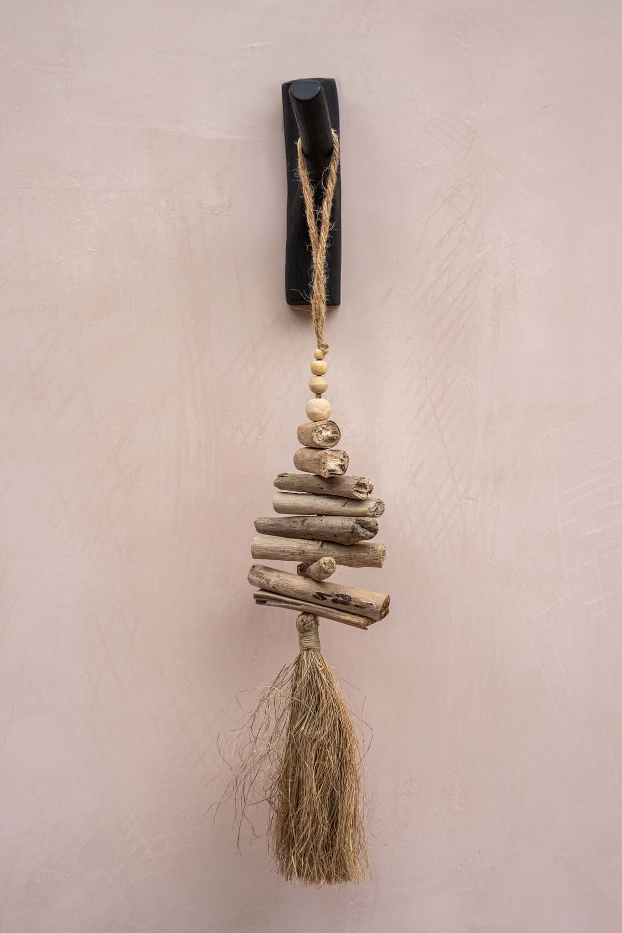 Zwarte teak houten kapstokhaak met decoratieve hanger van drijfhout en touw, perfect voor creatief ophangen in elke kamer.